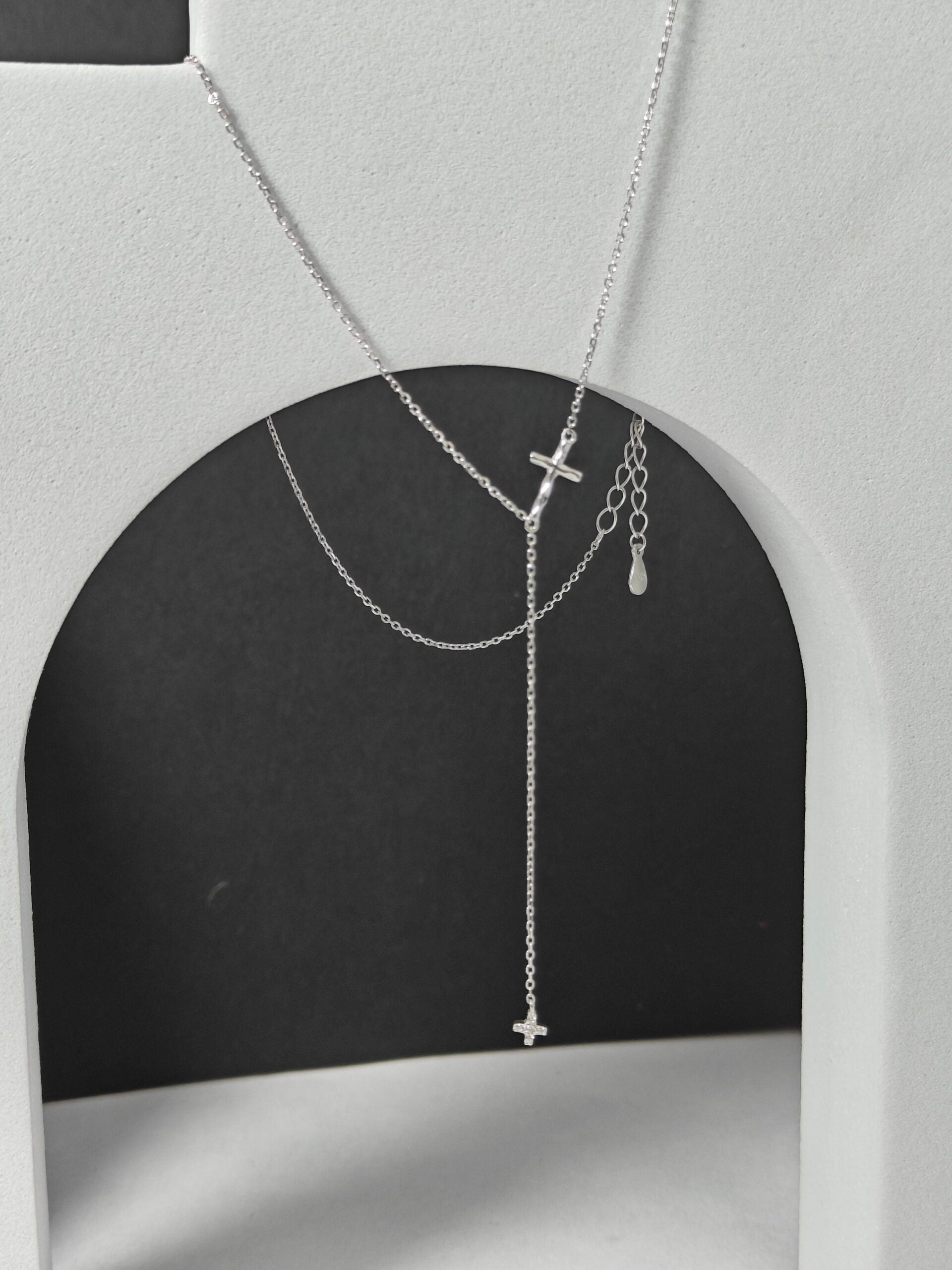 Silver necklace with cross pendants on a gray background